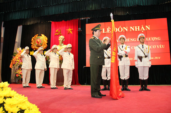 Đại tướng Trần Đại Quang gắn Huy hiệu Anh hùng lực lượng vũ trang nhân dân lên Cờ truyền thống của Cơ yếu Công an Nhân dân